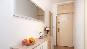 A hallway with a wooden counter, a mirror, a door, and a small vase with flowers. - Apartment Anica (Split)