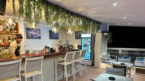 Zona bar con barista, un frigobar e posti a sedere con vista.