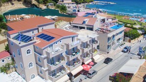 Un hotel sul lungomare con diversi piani, balconi e una zona piscina sul tetto.