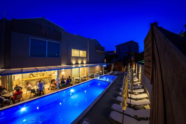 A swimming pool area with lounge chairs and a bar. - Porto Planos Beach Hotel (Zakynthos)