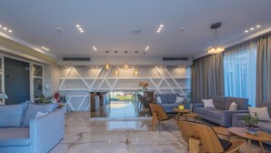 Una hall d'hotel moderna con un'area salotto, una reception e vista sullo spazio esterno.