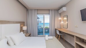 Una camera d'albergo con un letto, una scrivania, una sedia e un'ampia finestra con tende.