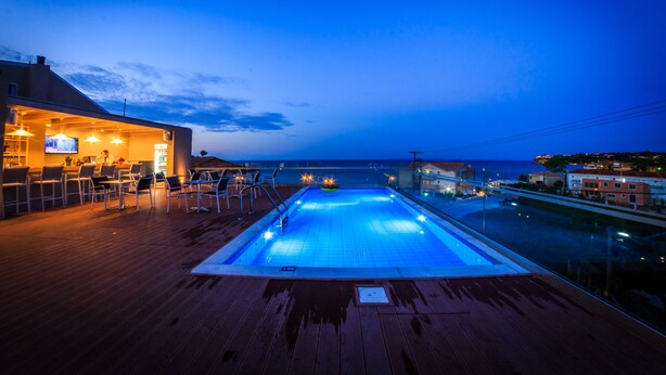 Area piscina con vista sul mare, un bar e posti a sedere all'aperto.