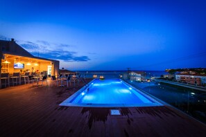 A pool area with a view of the sea, a bar, and outdoor seating. - Porto Planos Beach Hotel (Zakynthos)