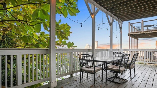 An outdoor patio with a white railing, a table with chairs, and string lights.
