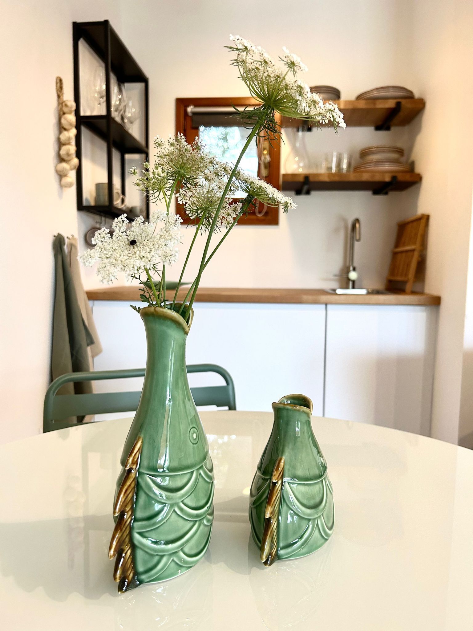 Two green ceramic vases with scalloped designs on a white table.