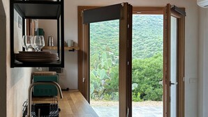 A modern kitchen with a wooden countertop, a built-in sink, and a view of a lush garden through a large sliding door.