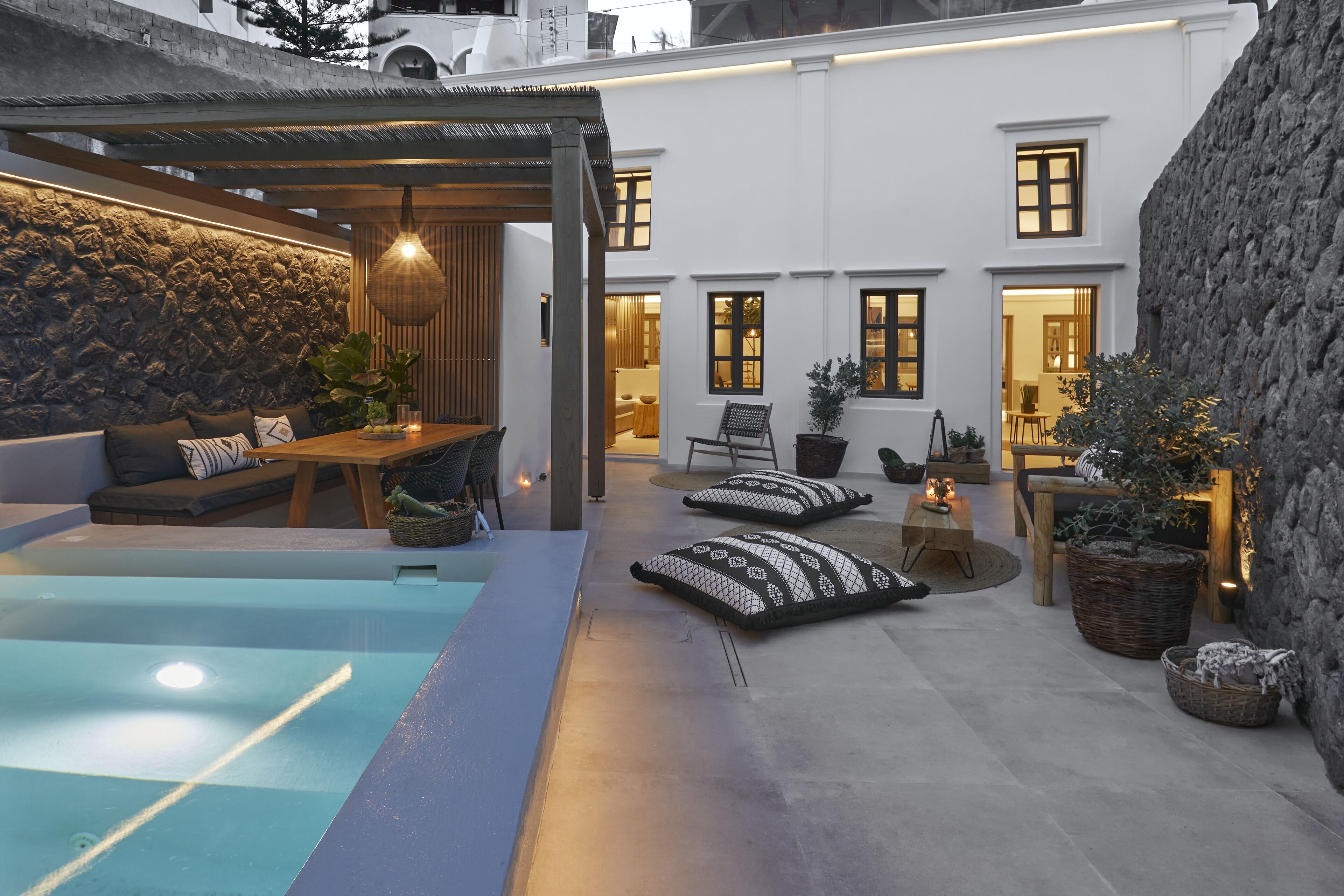 A modern outdoor living area with a pool, seating, and a stone wall.
