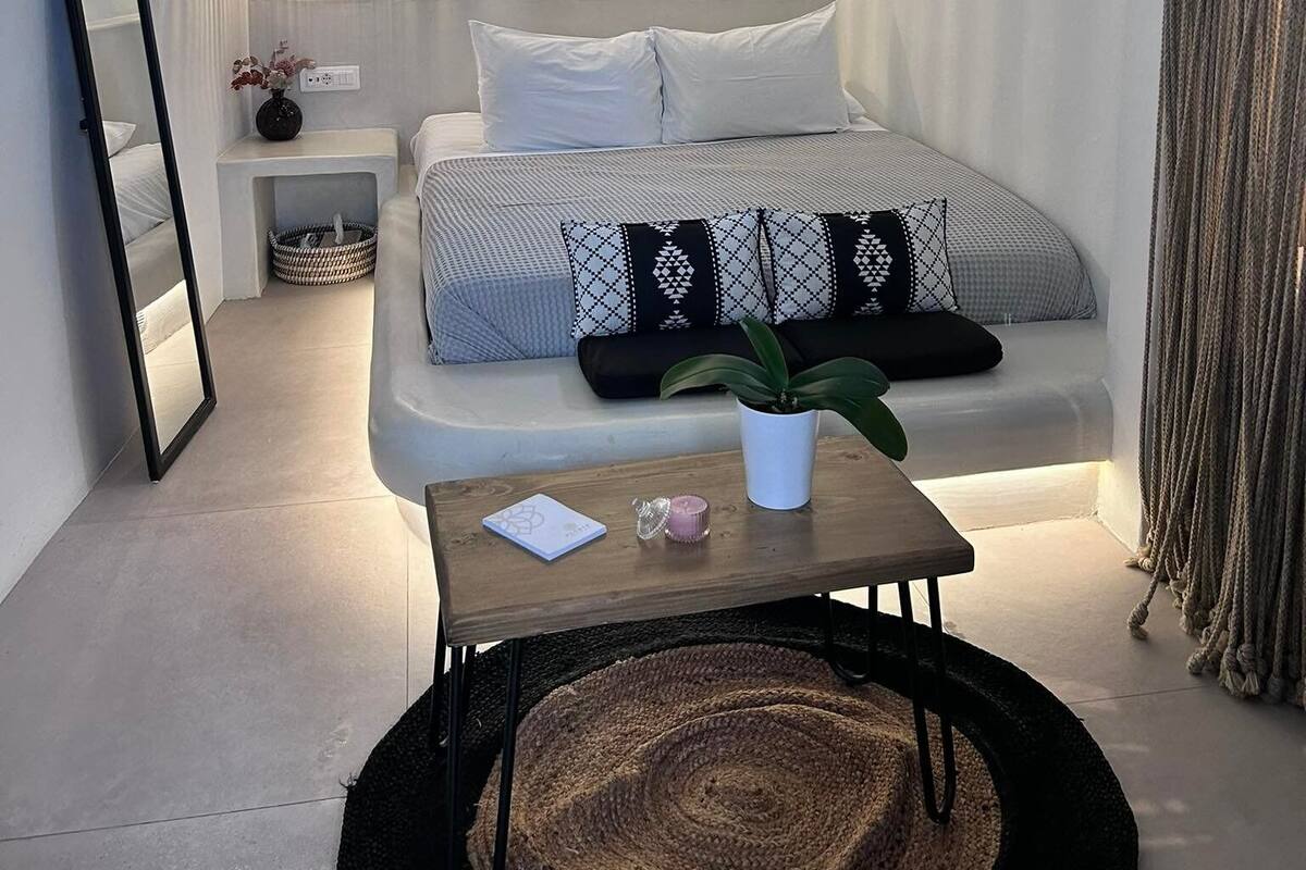 A modern bedroom with a bed, bedside table, lamp, and decorative wall hanging.