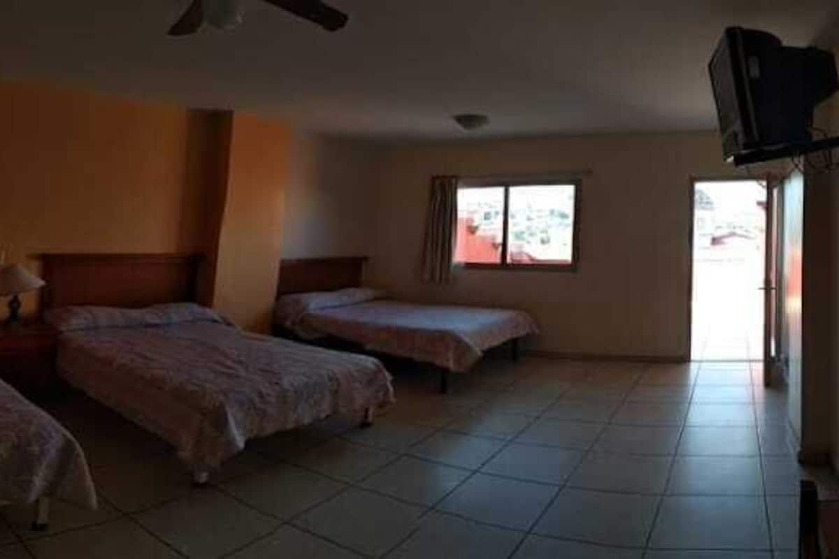 A hotel room with two beds, a ceiling fan, and a TV mounted on the wall.