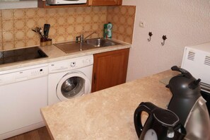 Eine kleine Küche mit Waschmaschine, Spüle und Wasserkocher.