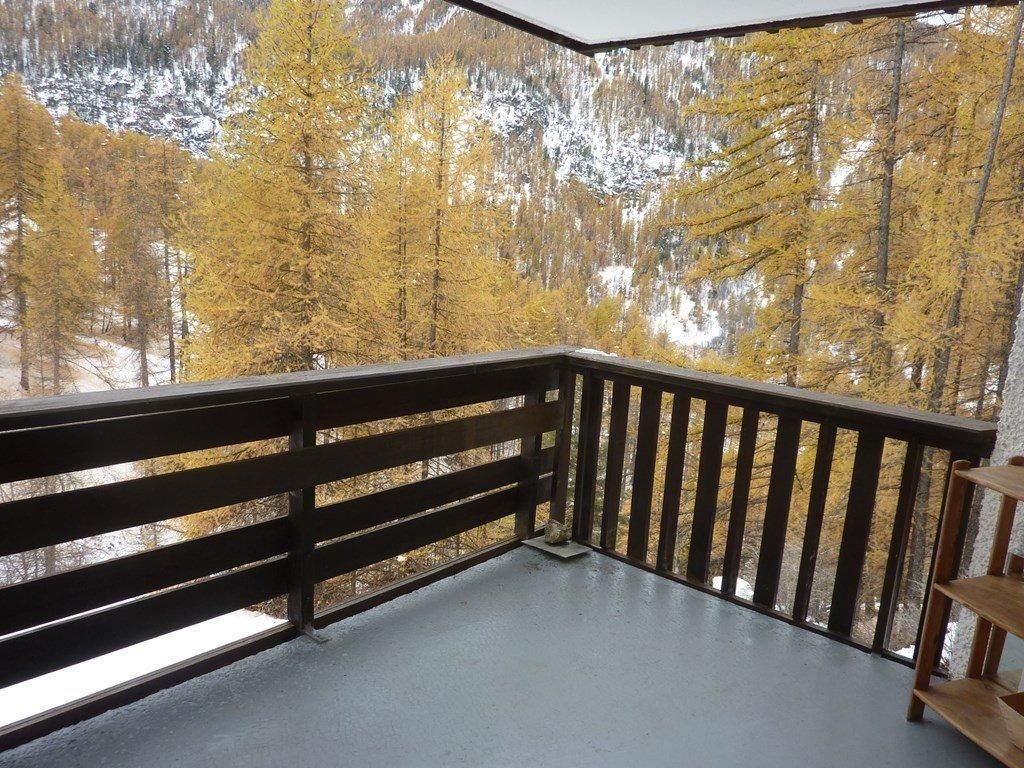 A balcony with a view of a forested area and a snow-covered mountain.