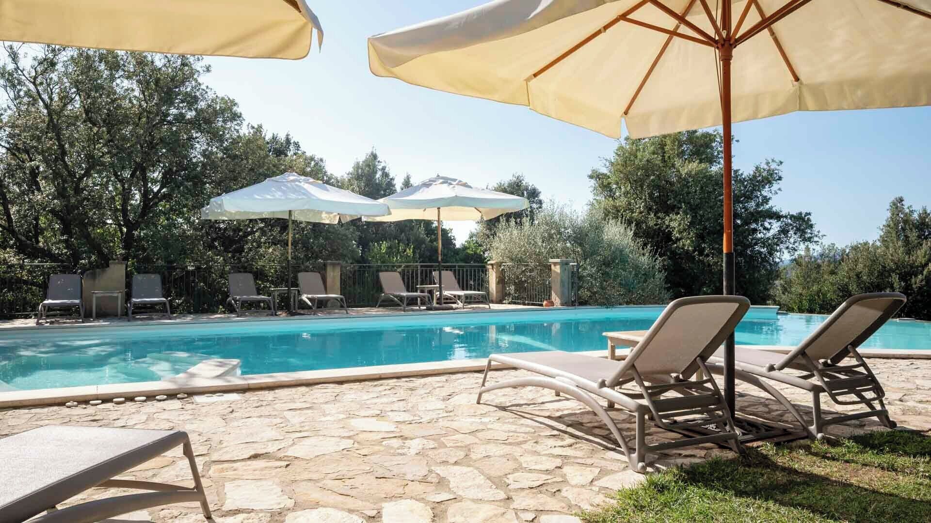 Un espace piscine équipé de chaises longues et de parasols.