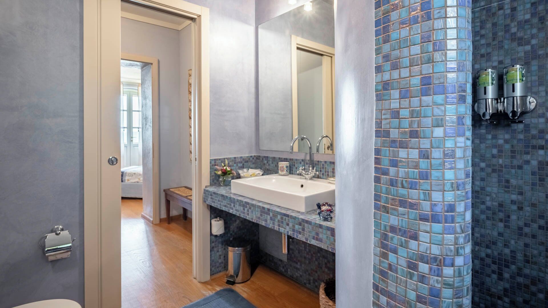 Une salle de bain moderne avec un grand miroir, un lavabo et un mur recouvert de carreaux.