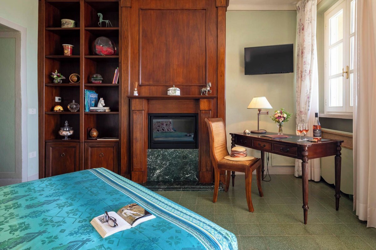 A room with a bed, a desk, a chair, a television, and a bookshelf.