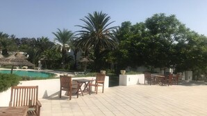 A poolside area with outdoor seating and palm trees.