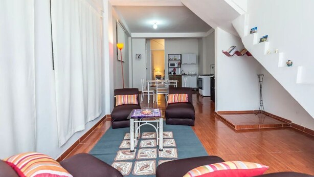 A modern living room with a sofa set, a coffee table, and a dining area in the background. - Rafita's House private apartment with good location (downtown and apt) (Cusco)