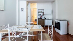 A compact kitchen with a microwave, oven, and cabinets. There is a dining area with a table and chairs. - Rafita's House private apartment with good location (downtown and apt) (Cusco)
