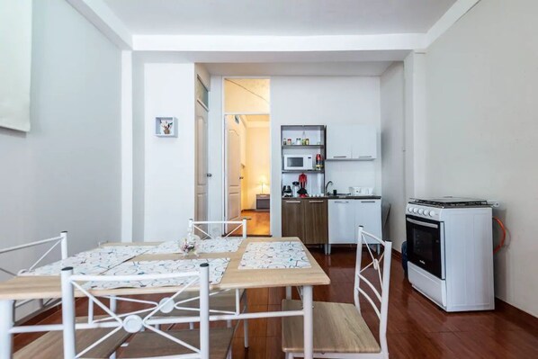 A compact kitchen with a microwave, oven, and cabinets. There is a dining area with a table and chairs.
