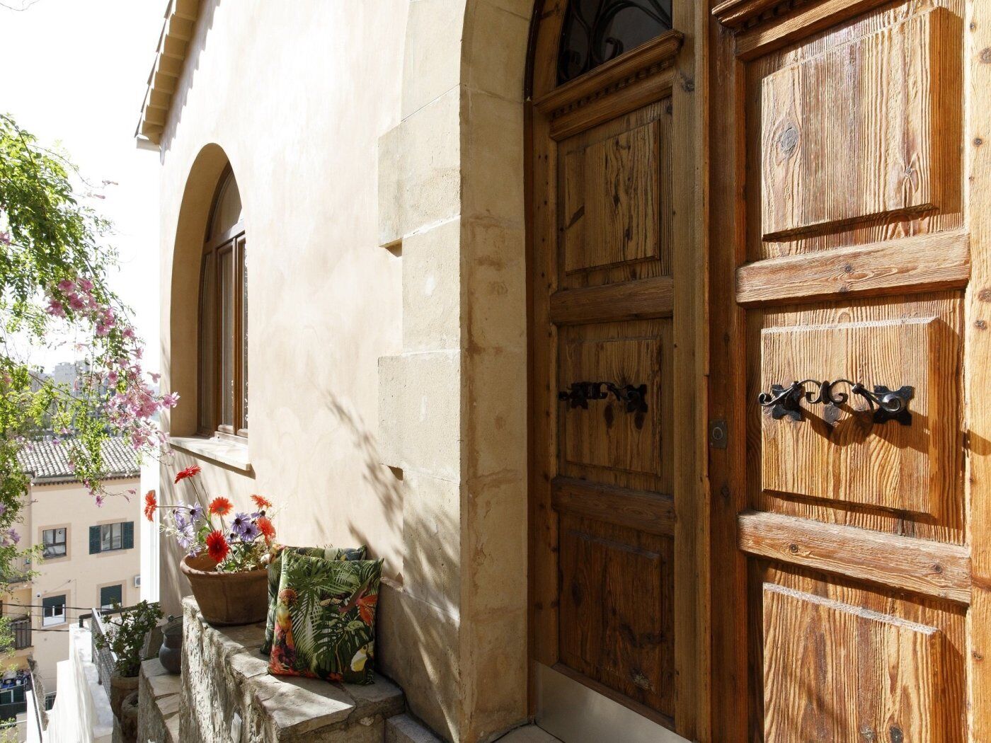 A wooden door with a metal handle and a window with a view of buildings.