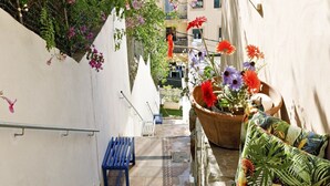 A narrow outdoor staircase with stone steps, a blue bench, and a potted plant with colorful flowers. - Villa Can Moya (Palma)