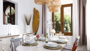 A dining area with a round table set for six, surrounded by white chairs. - Villa Can Moya (Palma)