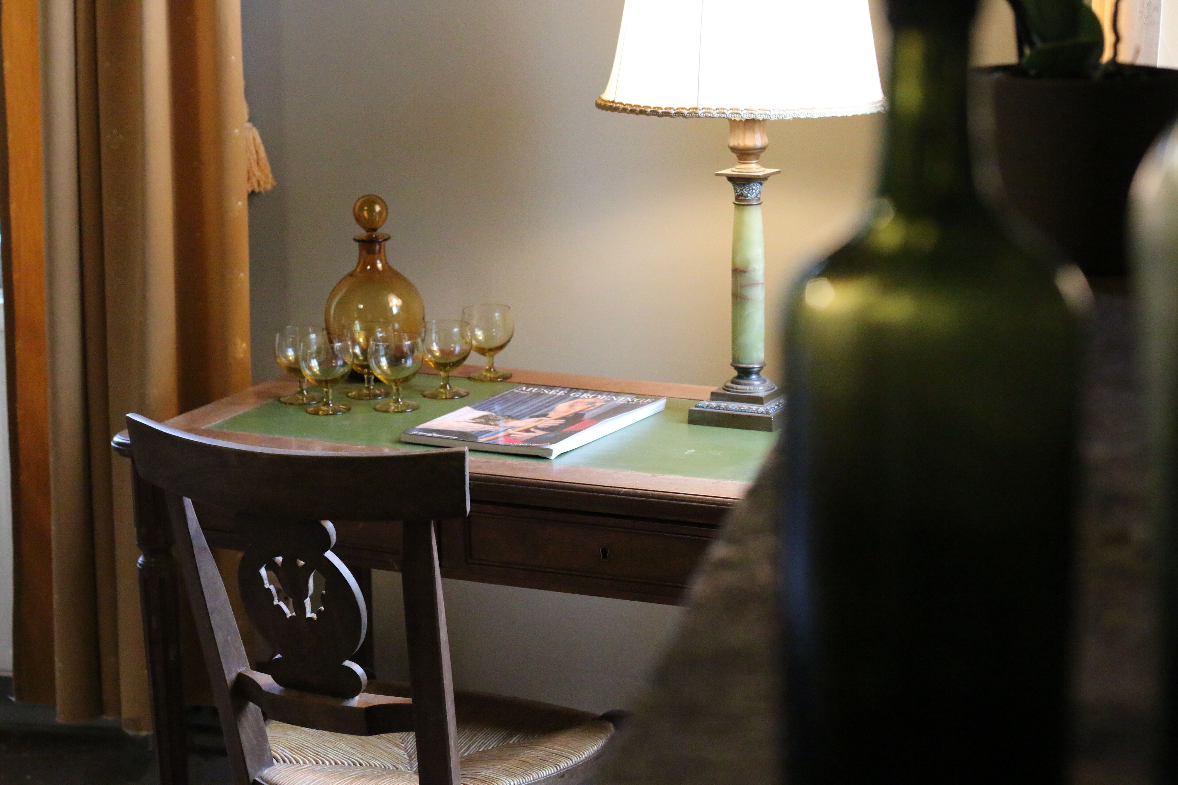 Una mesa de comedor con mantel verde, una lámpara y varias copas de vino.