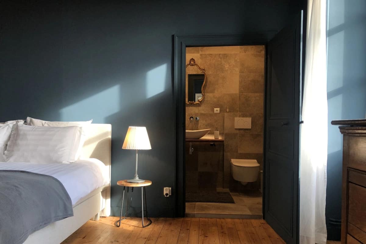 Un dormitorio con cama, lámpara de noche y suelo de madera.