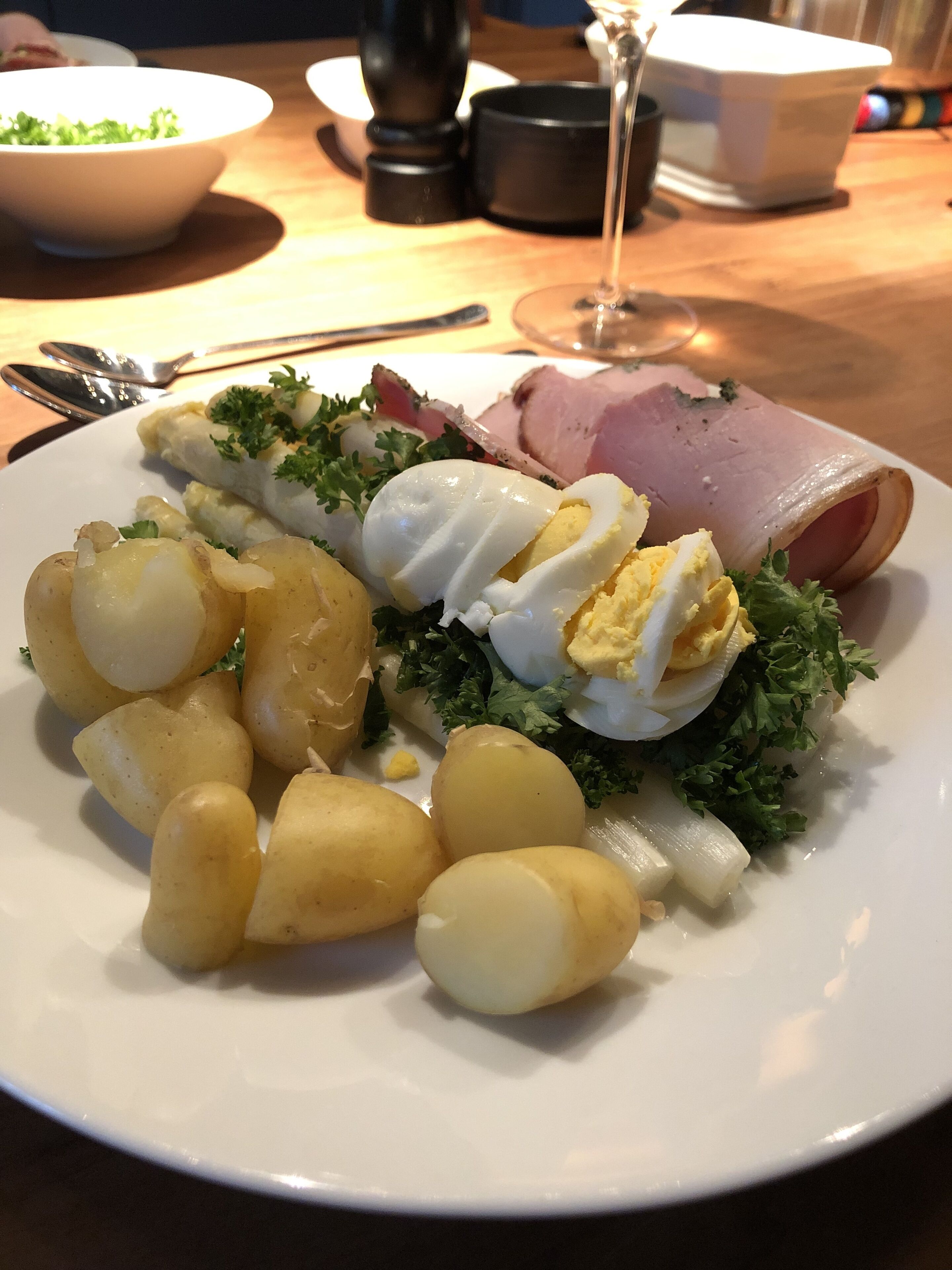 Un plato de comida con huevos cocidos, jamón y patatas.