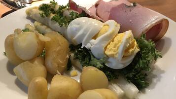 Un plato de comida con huevos cocidos, jamón y patatas.