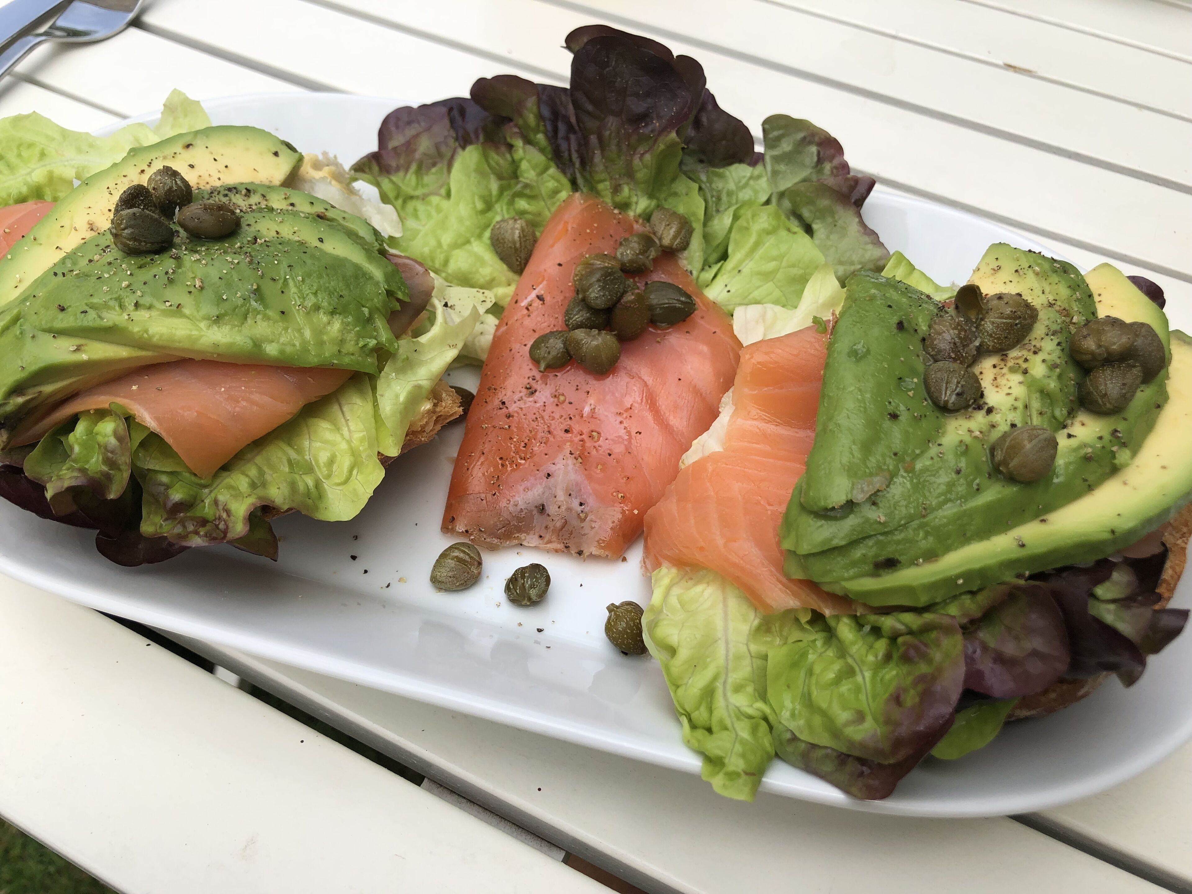 Un plato de comida con aguacate, salmón y lechuga.
