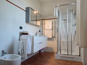 Comfort tweepersoonskamer | Badkamer | Een bad/douchecombinatie, een haardroger, een bidet, handdoeken