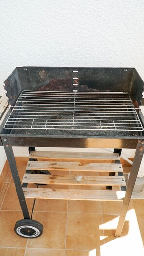 Una parrilla portátil con rejilla de metal, estructura de metal negro y listones de madera para soporte.