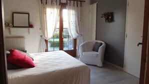Une chambre à coucher avec un lit, une chaise, un radiateur et une fenêtre avec des rideaux.