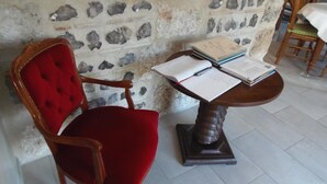 Ein Holzstuhl mit rotem Kissen und ein Tisch mit einem offenen Buch und Papier.