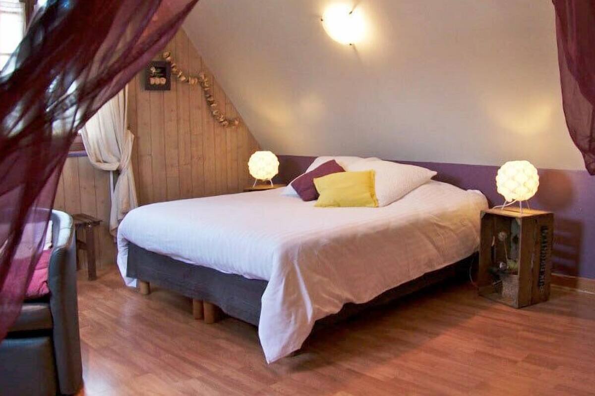 Un dormitorio con cama, dos lámparas de noche y cabecero de madera.