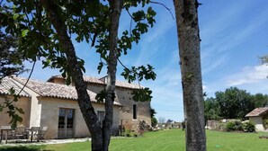 A rustic stone house with a tiled roof, a grassy yard, and a small patio with outdoor furniture. - B&B Clos de Saint-Maime (Saint-Maime-de-Pereyrol)