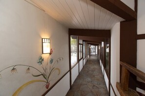 A corridor with a stone floor, wooden beams, and a wall with floral artwork.