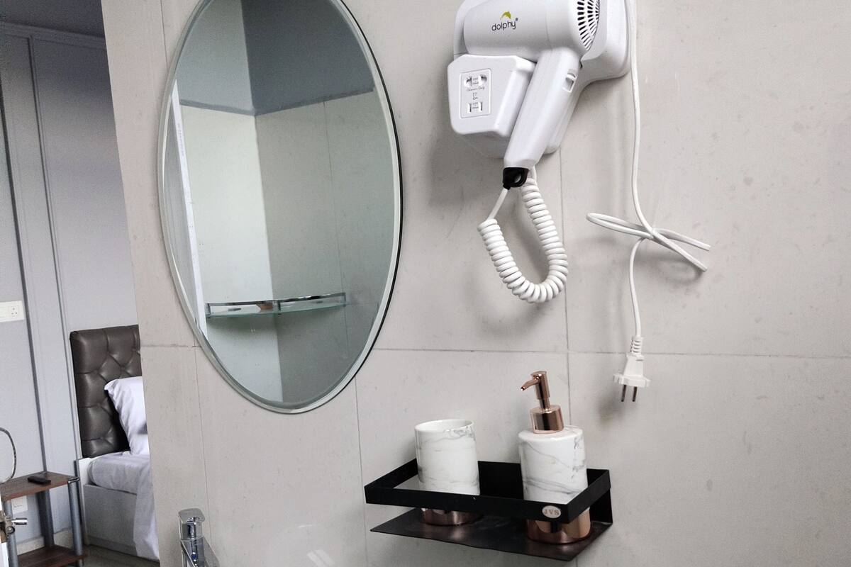 A bathroom with a sink, mirror, towel rack, and hairdryer.