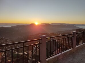 A balcony with a metal railing overlooking a cityscape during sunset. - The 1998 Homestay (Aizawl)