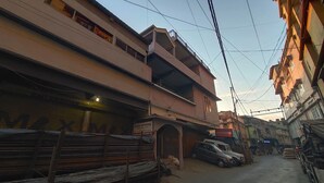 A narrow street with buildings on either side, a sign for 'JONAH ENTERPRISE', and a parked car. - The 1998 Homestay (Aizawl)