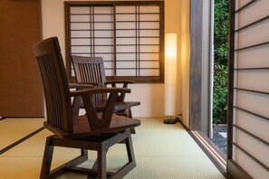 A traditional Japanese room with tatami flooring, a shoji screen, and a low table with chairs.