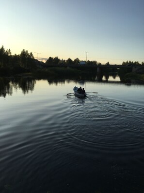 Een rustige rivier met een klein bootje, waarin twee personen zitten.