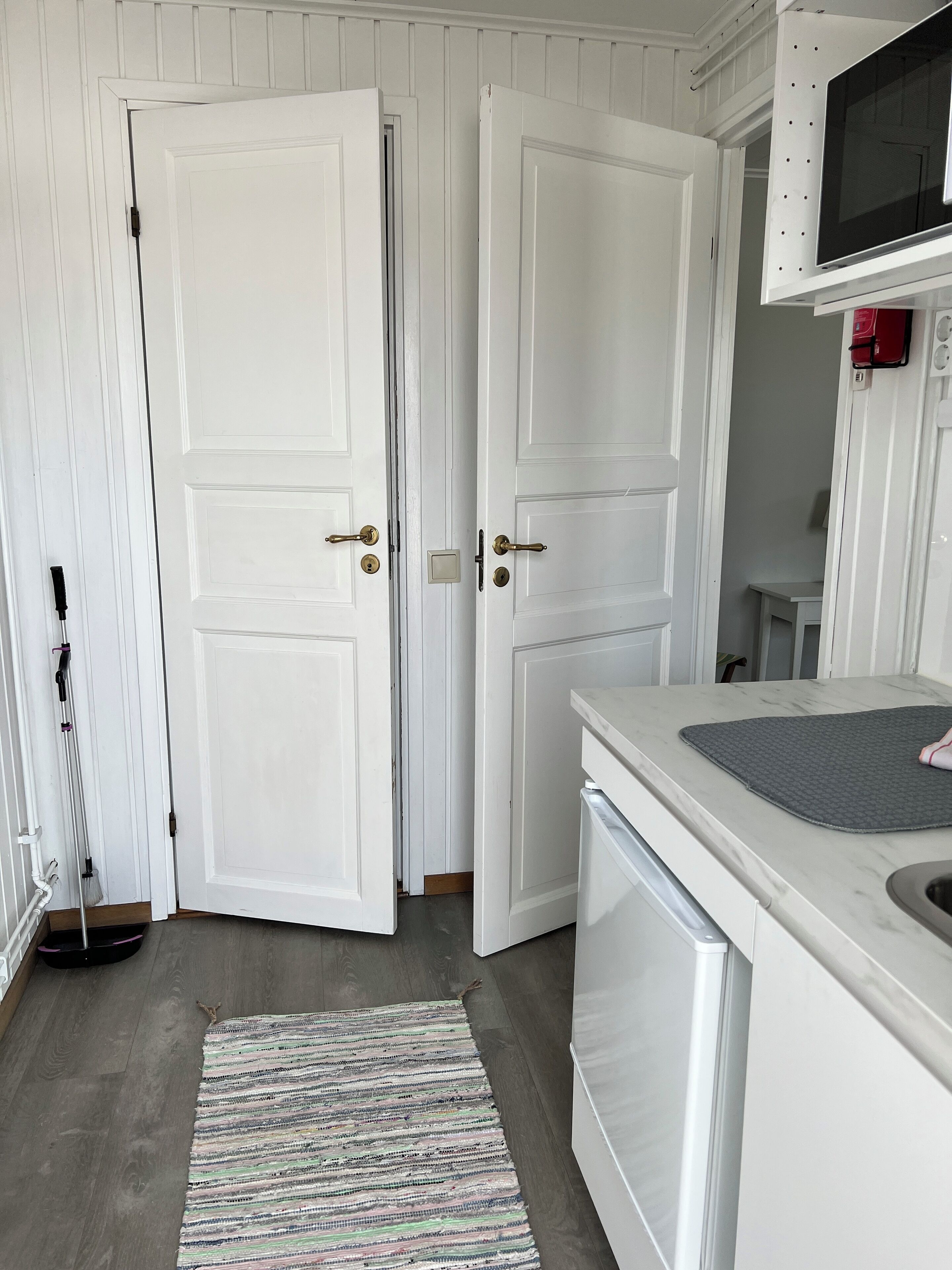 A kitchen with white cabinetry, a microwave, and a small table.