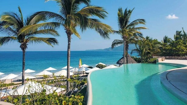 A poolside area with palm trees, umbrellas, and a view of the ocean. - Hacienda de Mita Golf View Beach Clubs & Golf Cart (Punta de Mita)