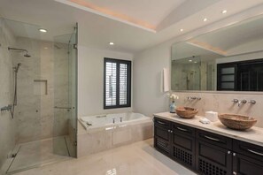 Une salle de bain moderne dotée d’une douche à parois de verre, d’une baignoire sur pieds et d’un meuble-lavabo avec deux grands bacs.