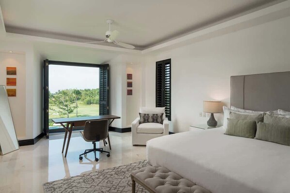 Une chambre moderne avec un grand lit, un bureau et une chaise. La fenêtre offre une vue sur la verdure.