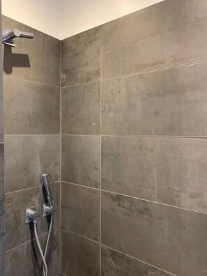 Ein Duschbereich mit modernem Design, ausgestattet mit einer wandmontierten Duschbrause und einem Handbrause-Anschluss.