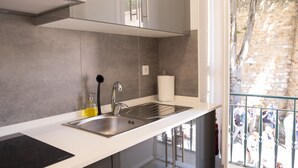 A modern kitchen with a stainless steel sink, a built-in stove, and a large window overlooking a stone wall. - Conqvistador 101 Homes (Lisboa)