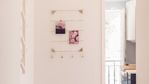 A hallway with a wooden floor, a white door, and a wall-mounted artwork. - Conqvistador 101 Homes (Lisboa)